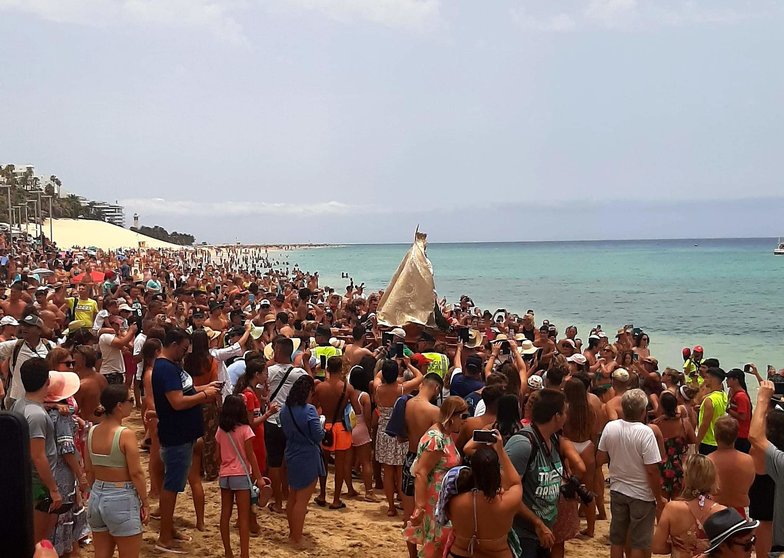 Groupe de personnes sur la plage avec la Vierge du Carmen sur le rivage, capturant l'essence des Fiestas del Carmen à Las Palmas