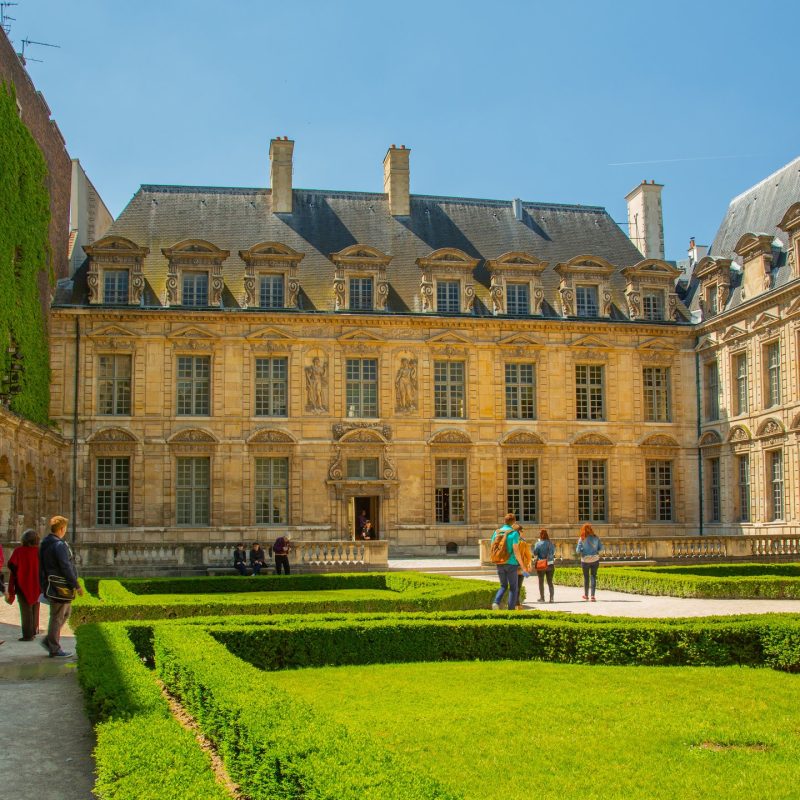 Jardin verdoyant avec un palais en arrière-plan, situé dans le quartier de Le Marais à Paris