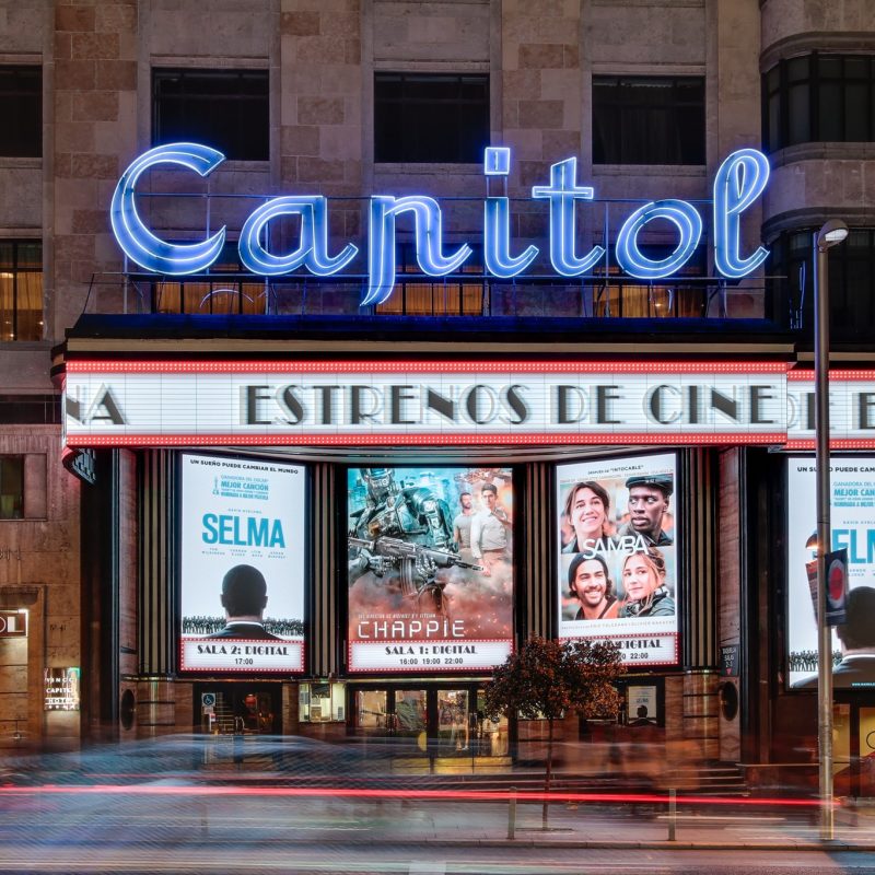 Exterior view of the Capitol Cinema in Madrid, featuring its iconic Art Deco facade and neon lights