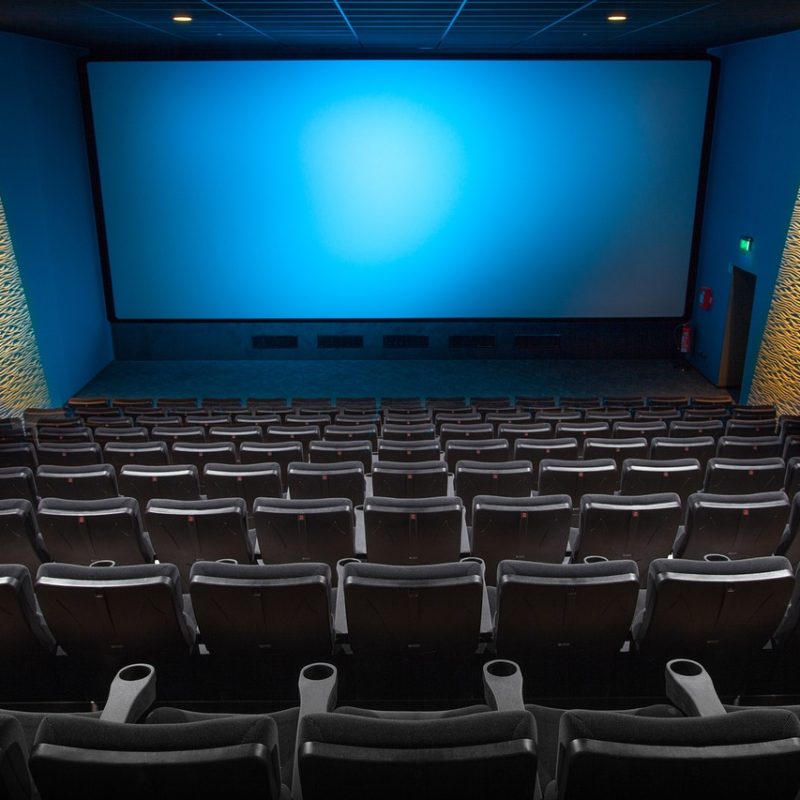 Vue intérieure d'une salle de cinéma à Madrid, avec des sièges en velours rouge et un grand écran au fond