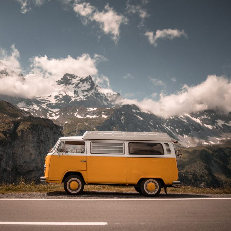 Una furgoneta de viaje con montañas nevadas al fondo, ilustrando cómo hacer viajes económicos