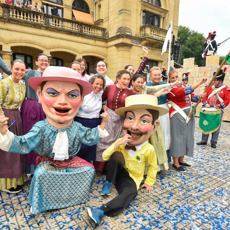 Gigantes y cabezudos desfilan por las calles de San Sebastián durante la Semana Grande de San Sebastián, rodeados de espectadores que disfrutan del animado evento festivo