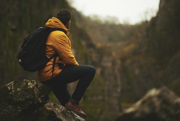 Chico sentado en una roca con una mochila, descansando después de una caminata en una ruta de senderismo en Valencia