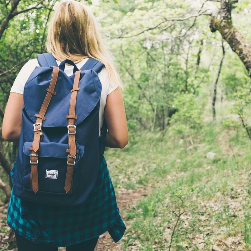 Fille de dos avec un sac à dos, marchant sur un sentier de randonnée à Valencia, entourée de nature