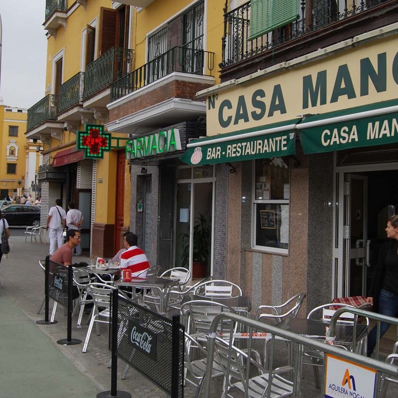 Exterior del bar Casa Manolo en Sevilla, mostrando su fachada tradicional y entrada acogedora