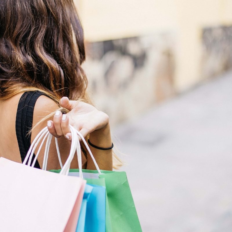 Mujer sosteniendo varias bolsas de compras mientras camina por una calle comercial en Las Palmas