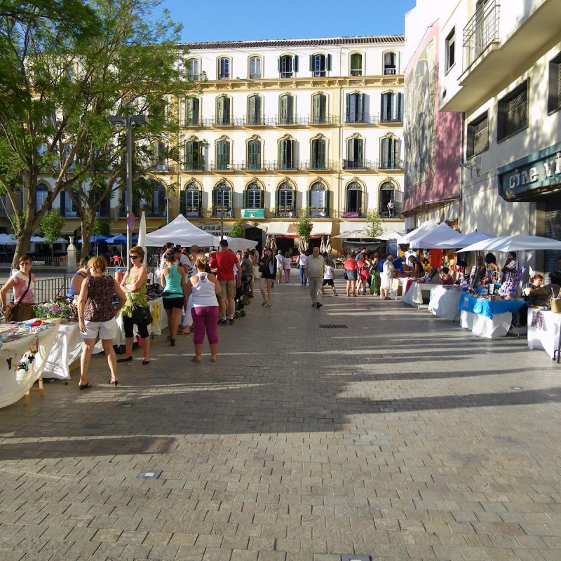 Mercado local en la Plaza de la Merced, Málaga, con puestos de artesanías y productos frescos durante un evento en octubre