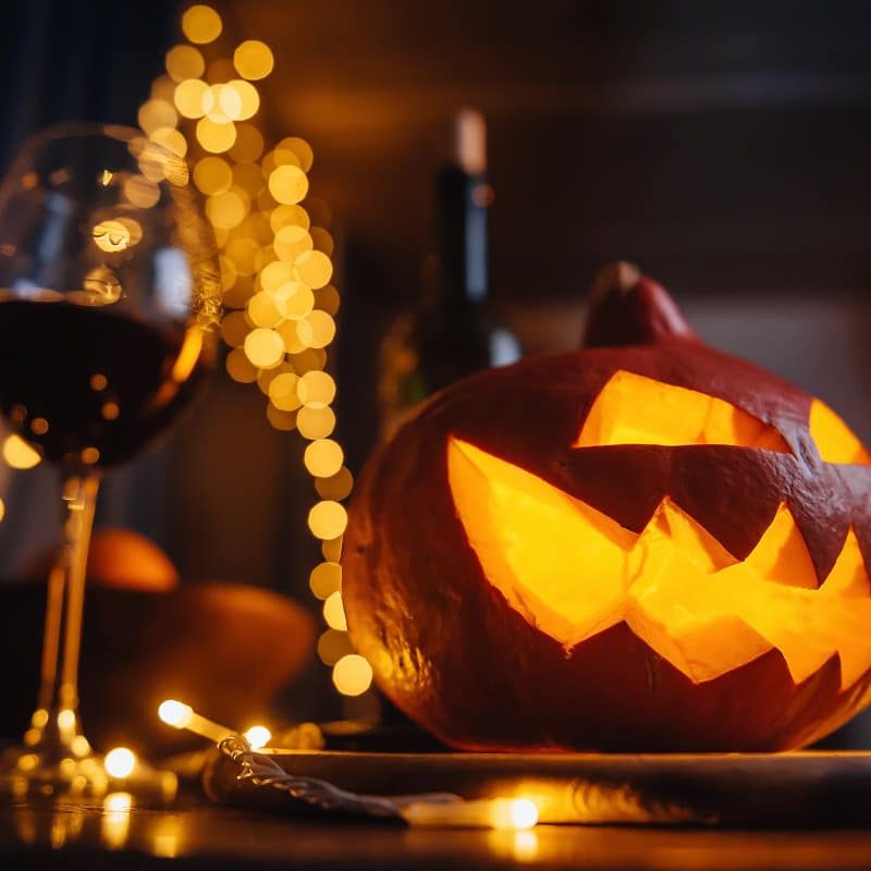 Calabaza decorativa de Halloween con una copa de vino al lado