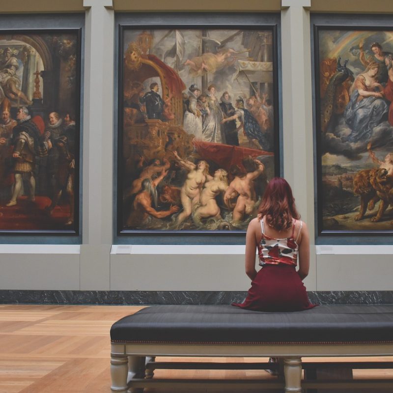 Une jeune femme regarde des tableaux dans un musée gratuit à Paris