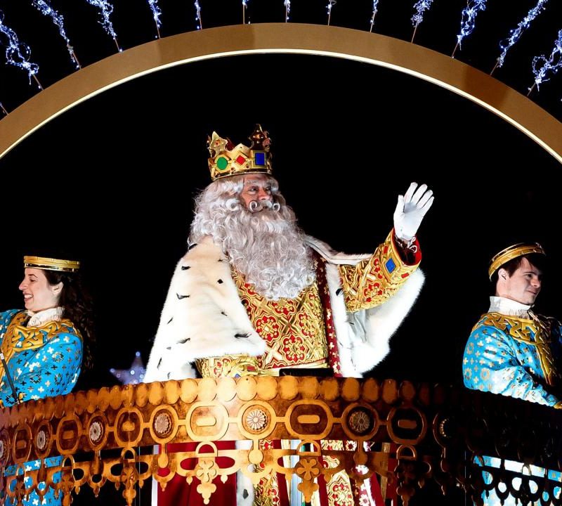 Un roi mage saluant la foule depuis un char, accompagné de ses pages, lors de la Cabalgata de Reyes à Madrid