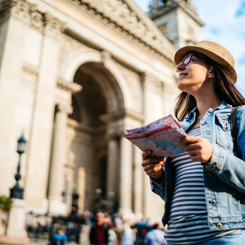 A girl standing in front of a monument holding a map