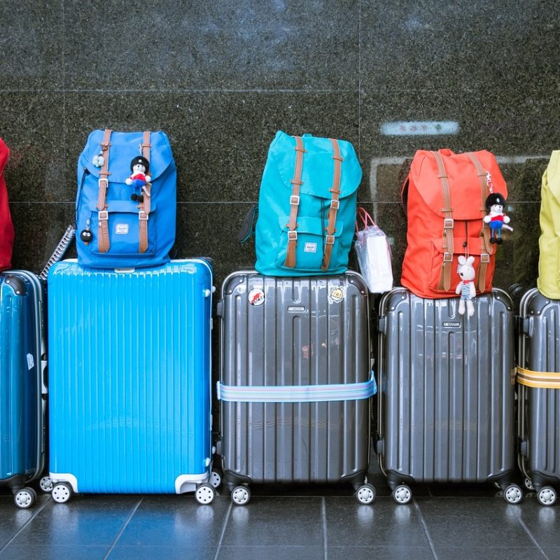 Fila de maletas con mochilas de colores colocadas encima, listas para ser guardadas