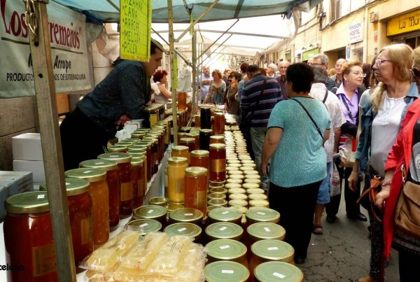 Stand de la Foire de Sant Ponç à Barcelone avec des pots de miel et des visiteurs en train d’acheter