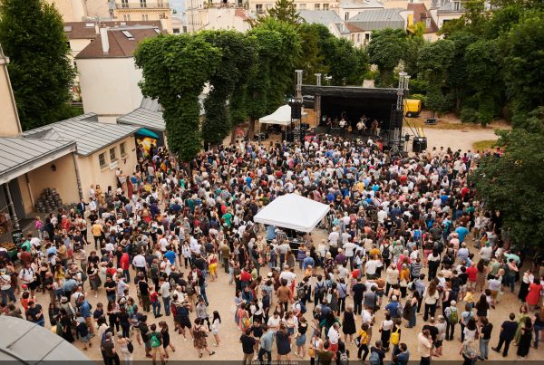 Multitud disfrutando de un concierto al aire libre en un jardín durante la Fiesta de la Música en París