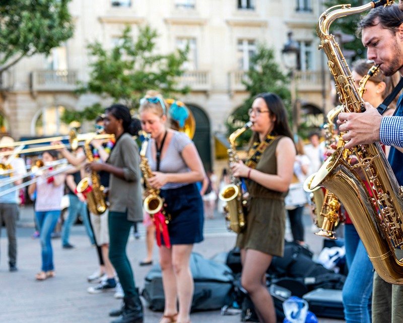 Musiciens jouant des instruments dans une rue animée de Paris lors de la Fête de la Musique