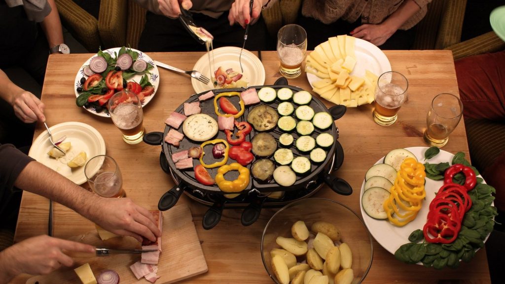 Raclette served at a table with diners enjoying a traditional dinner in Paris.