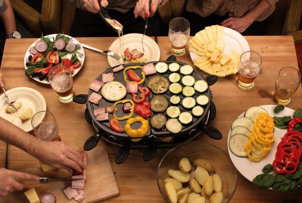 Raclette servida en una mesa con comensales disfrutando de una cena tradicional en París