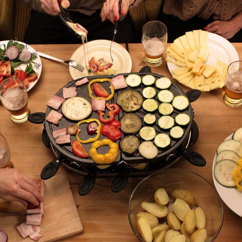 Raclette servida en una mesa con comensales disfrutando de una cena tradicional en París