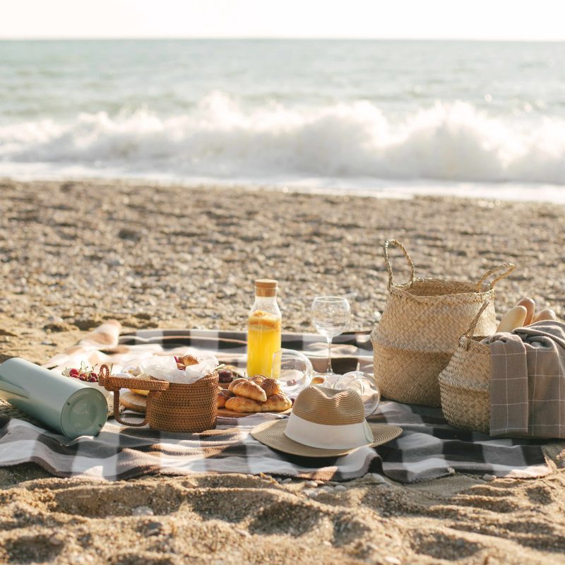 Pícnic romántico al atardecer en la playa de El Saler, Valencia, con mantas, frutas y bebidas sobre la arena