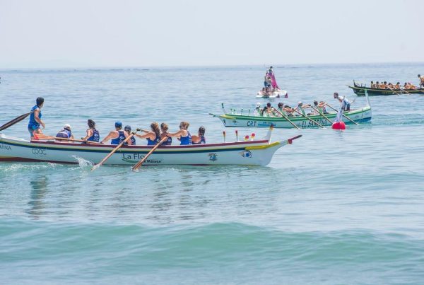 Traditional jábegas boat race taking place during the Maritime Festivities in Málaga, with teams rowing in unison near the coast