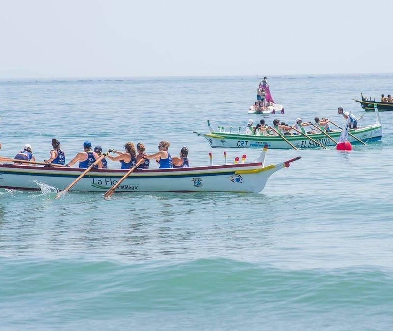 Traditional jábegas boat race taking place during the Maritime Festivities in Málaga, with teams rowing in unison near the coast