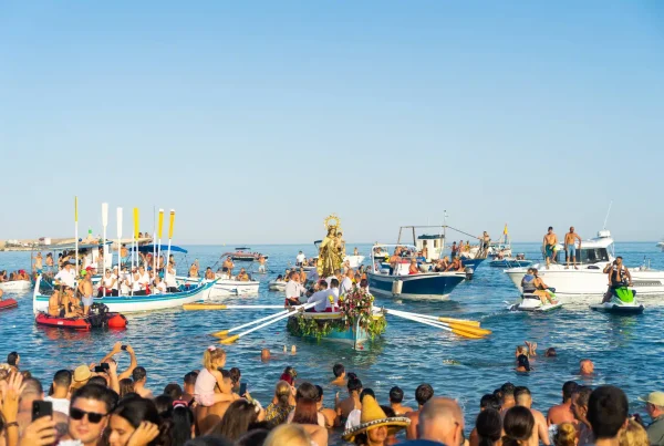 Procesión marítima con la Virgen del Carmen durante las Fiestas Marineras en Málaga, con embarcaciones engalanadas y devotos en el mar