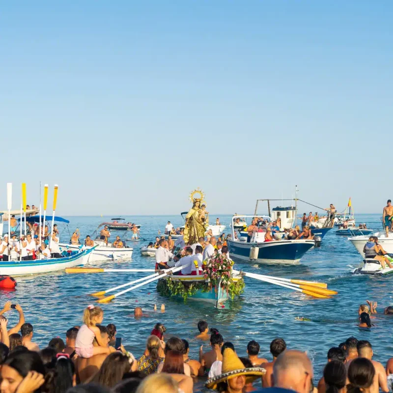 Procesión marítima con la Virgen del Carmen durante las Fiestas Marineras en Málaga, con embarcaciones engalanadas y devotos en el mar