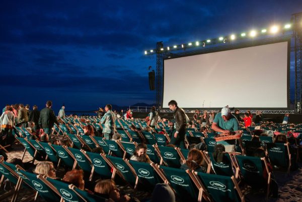 Séance de cinéma en plein air à Valence, avec des couples assis sur des chaises longues sous le ciel étoilé d’été