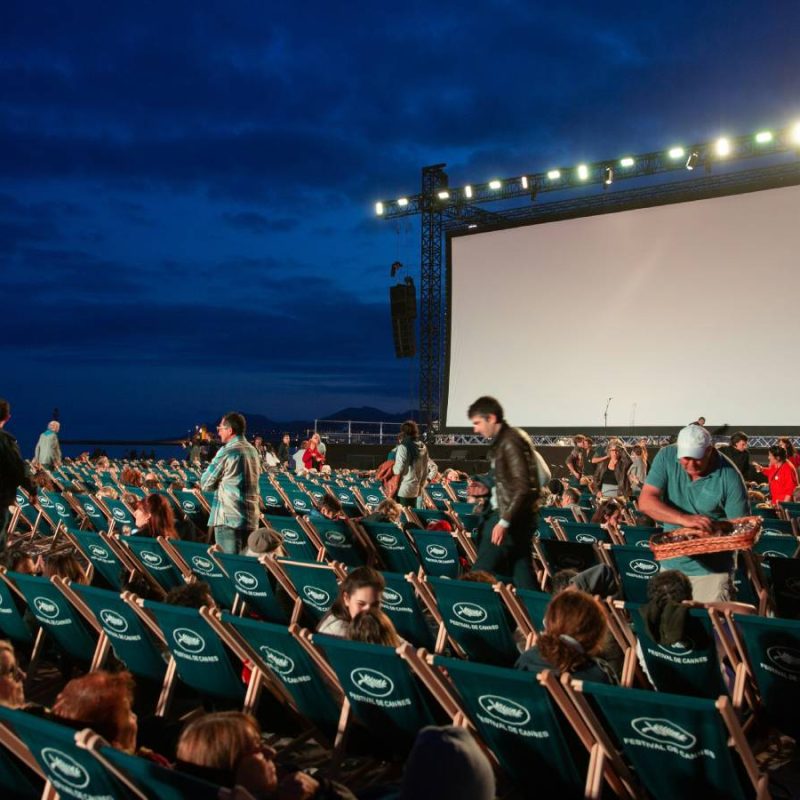 Séance de cinéma en plein air à Valence, avec des couples assis sur des chaises longues sous le ciel étoilé d’été