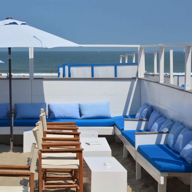 Beachside chiringuito in Benidorm with wooden tables, sun umbrellas, and the sea in the background on a sunny summer day