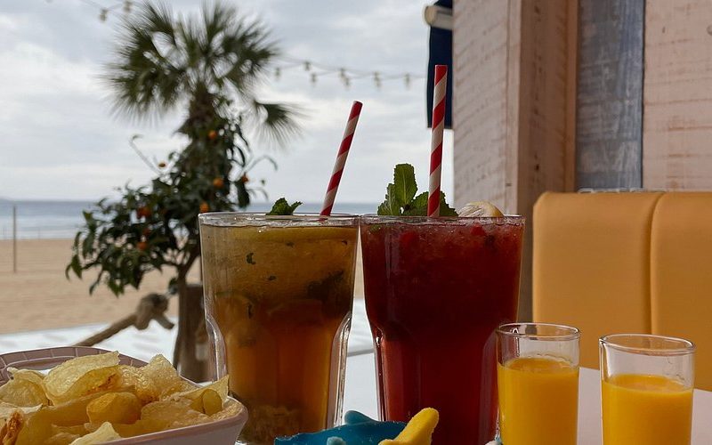 erres de mojito frais servis sur une table en bois dans un chiringuito de plage à Benidorm, avec vue sur la mer en arrière-plan